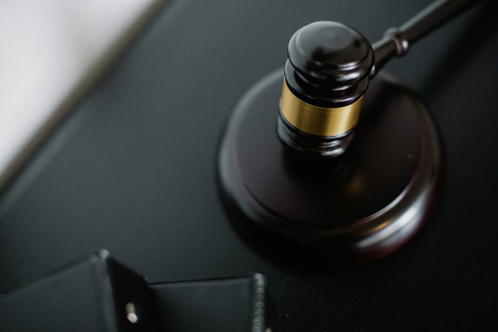 From above of wooden gavel on round surface near folders on table in courtroom