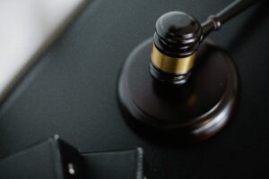 From above of wooden gavel on round surface near folders on table in courtroom